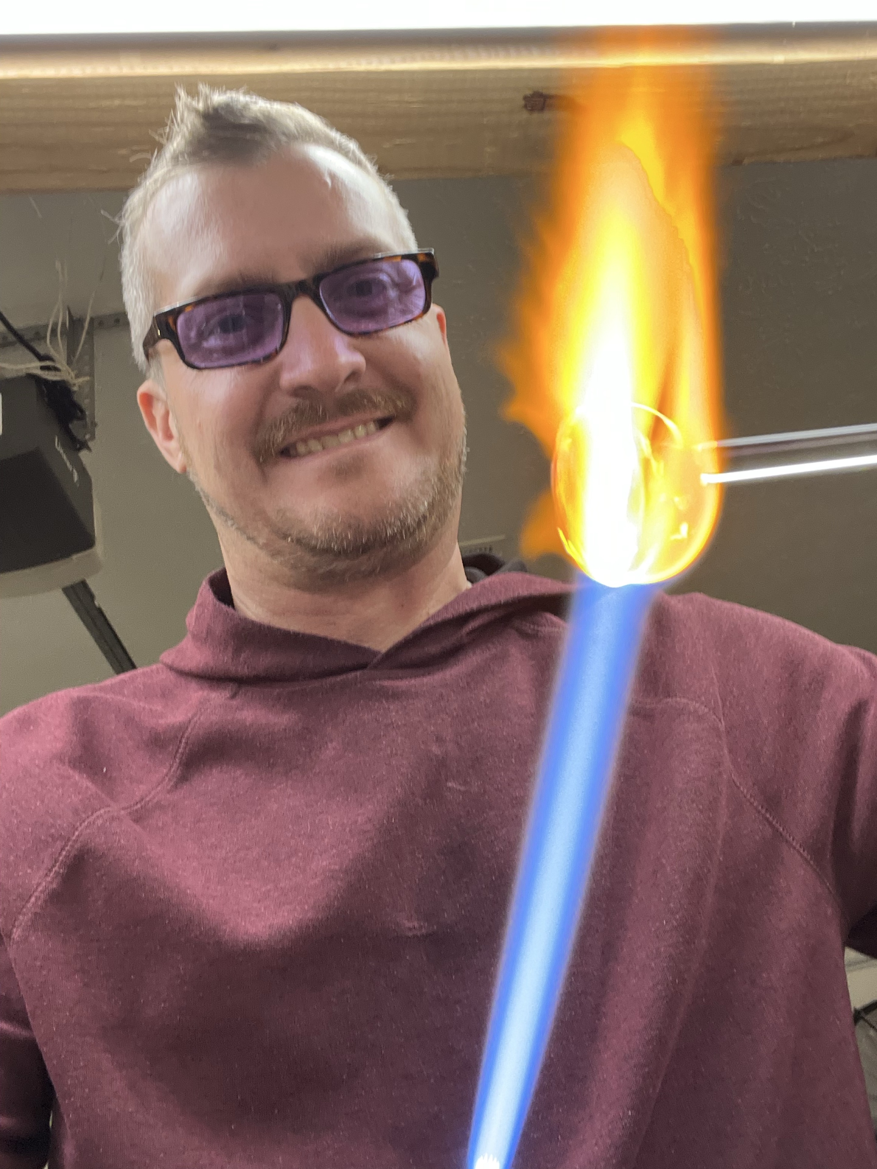 Will Stuckenberg smiling in protective glasses beside his torch