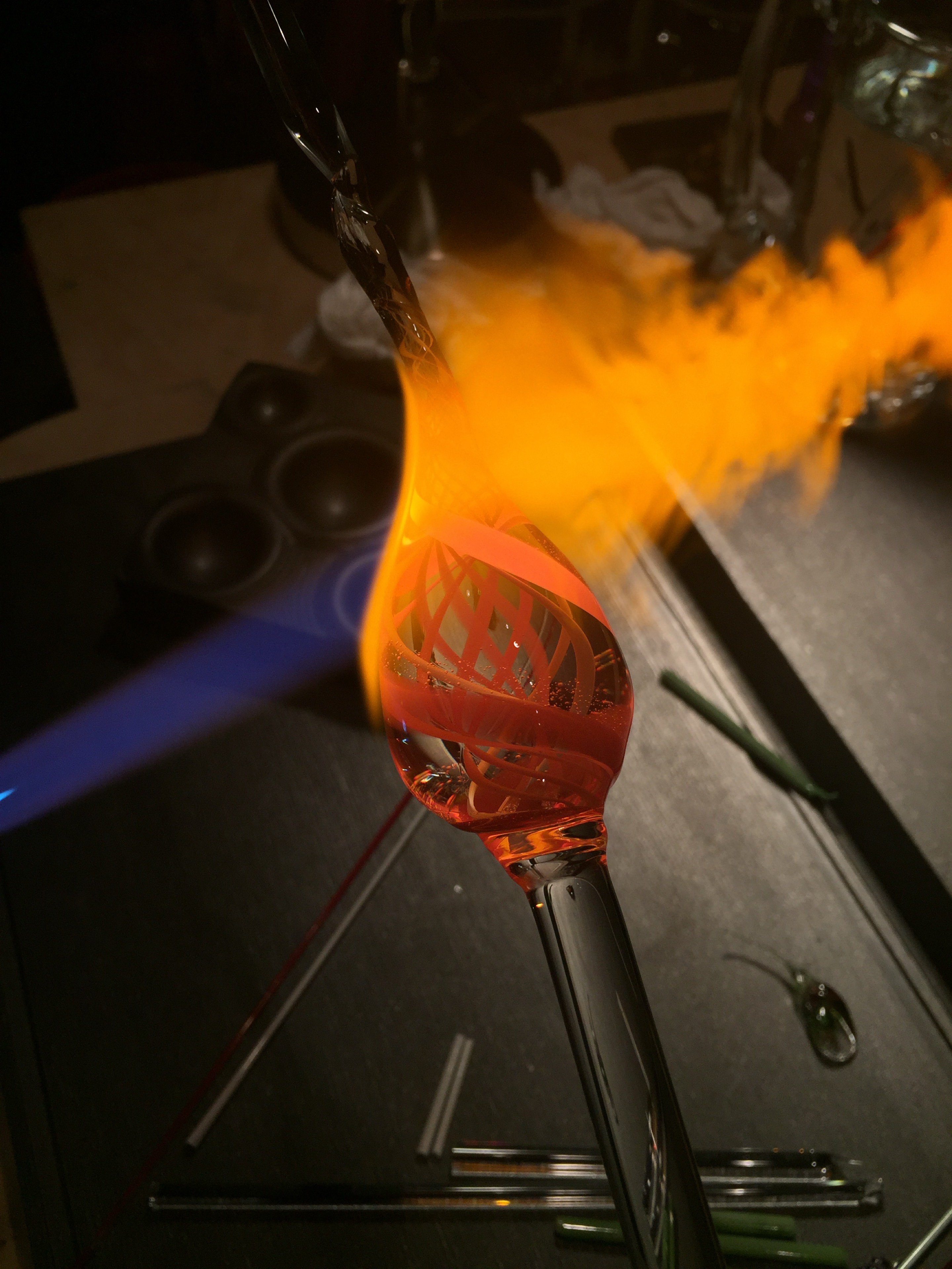 Glowing glass with crossing internal lines on a clear rod in the flame