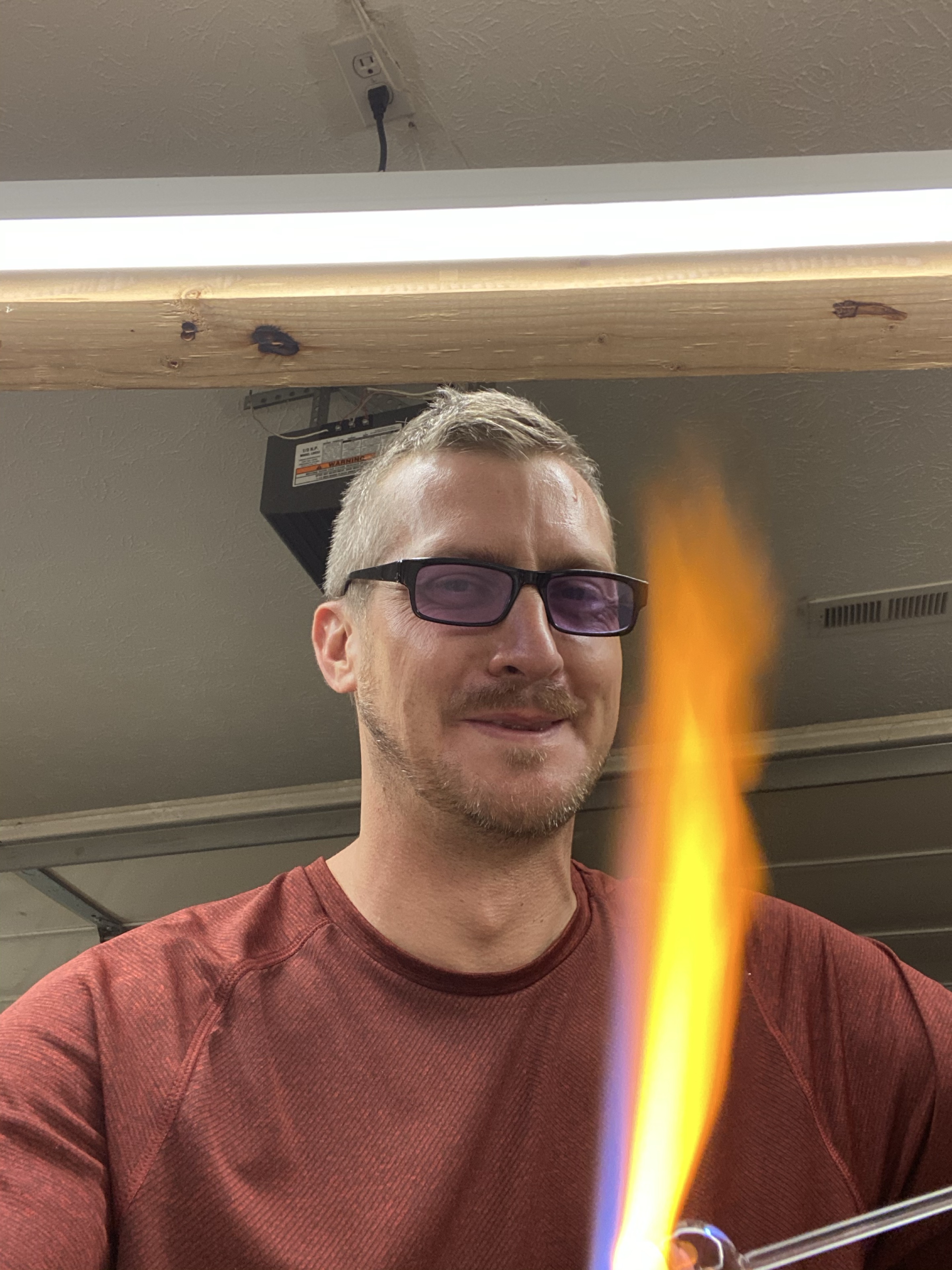 Will Stuckenberg in a red shirt beside an orange and blue torch flame