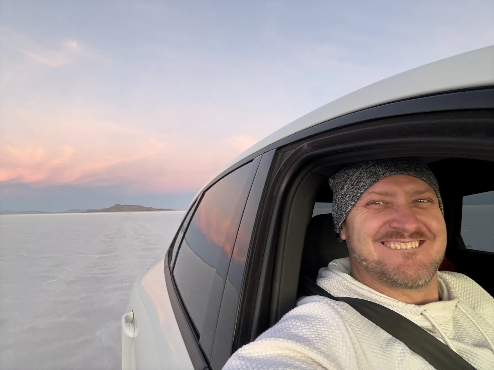Will Stuckenberg smiling from his vehicle on the salt flats at sunset