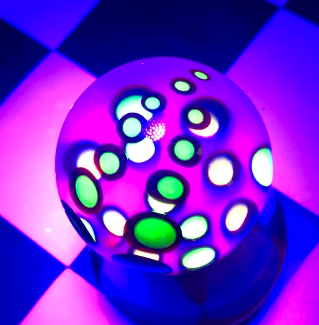 Multicolor Tentacle UV Marble under UV light with luminous green and yellow details against violet glass, view 1