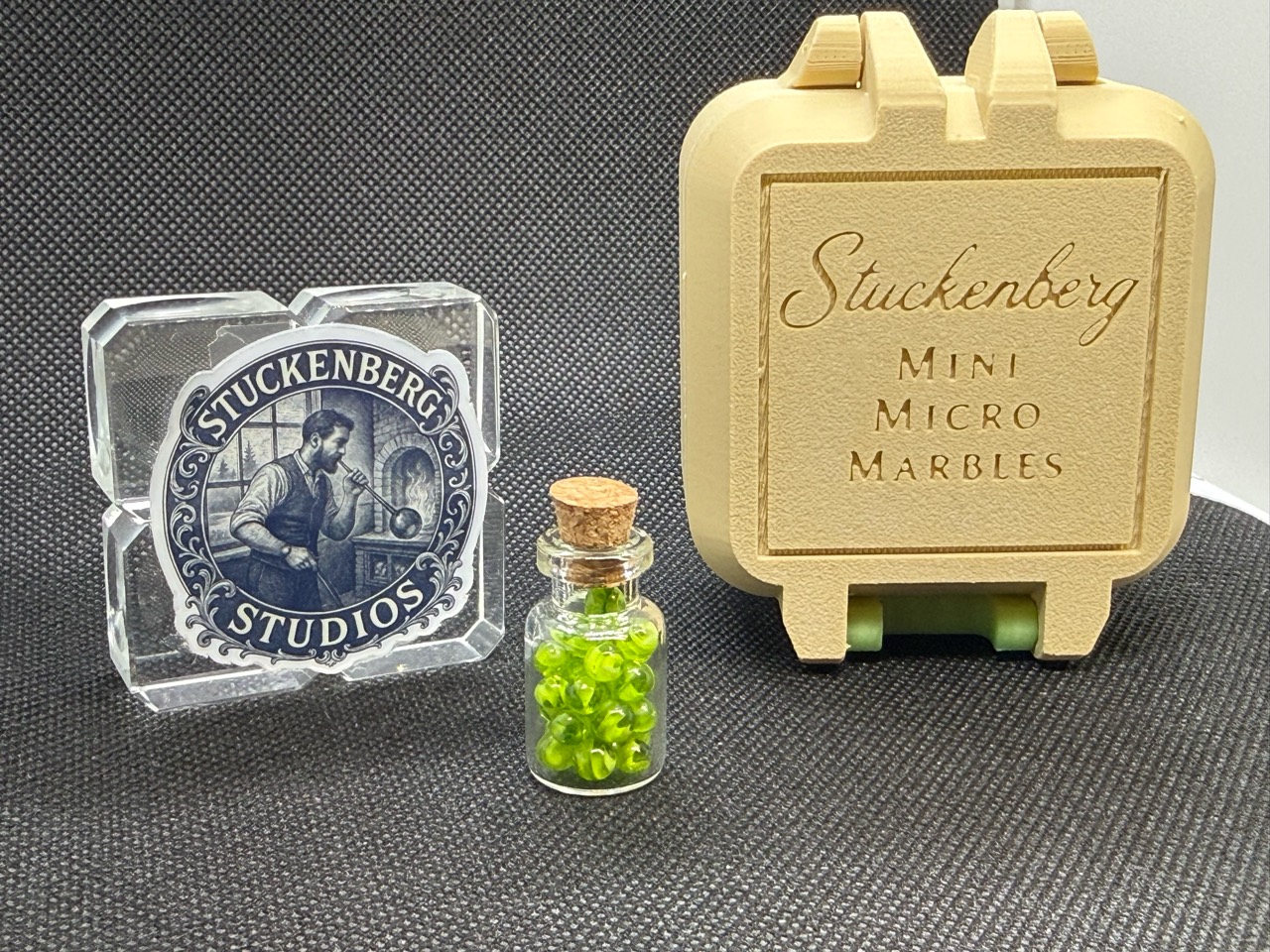 Neon Green Micro Marbles jar beside Stuckenberg Studios branding and an upright cream case