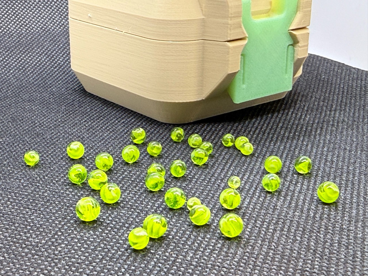 Neon Green Micro Marbles spread across a dark surface below a cream case