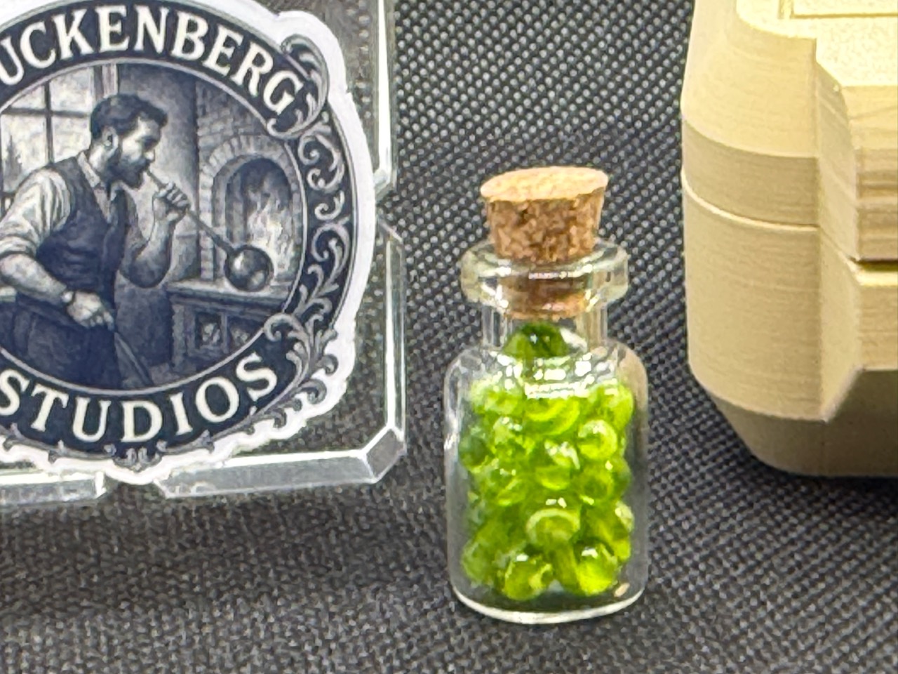 Corked jar of Neon Green Micro Marbles with the Stuckenberg Studios logo in the background