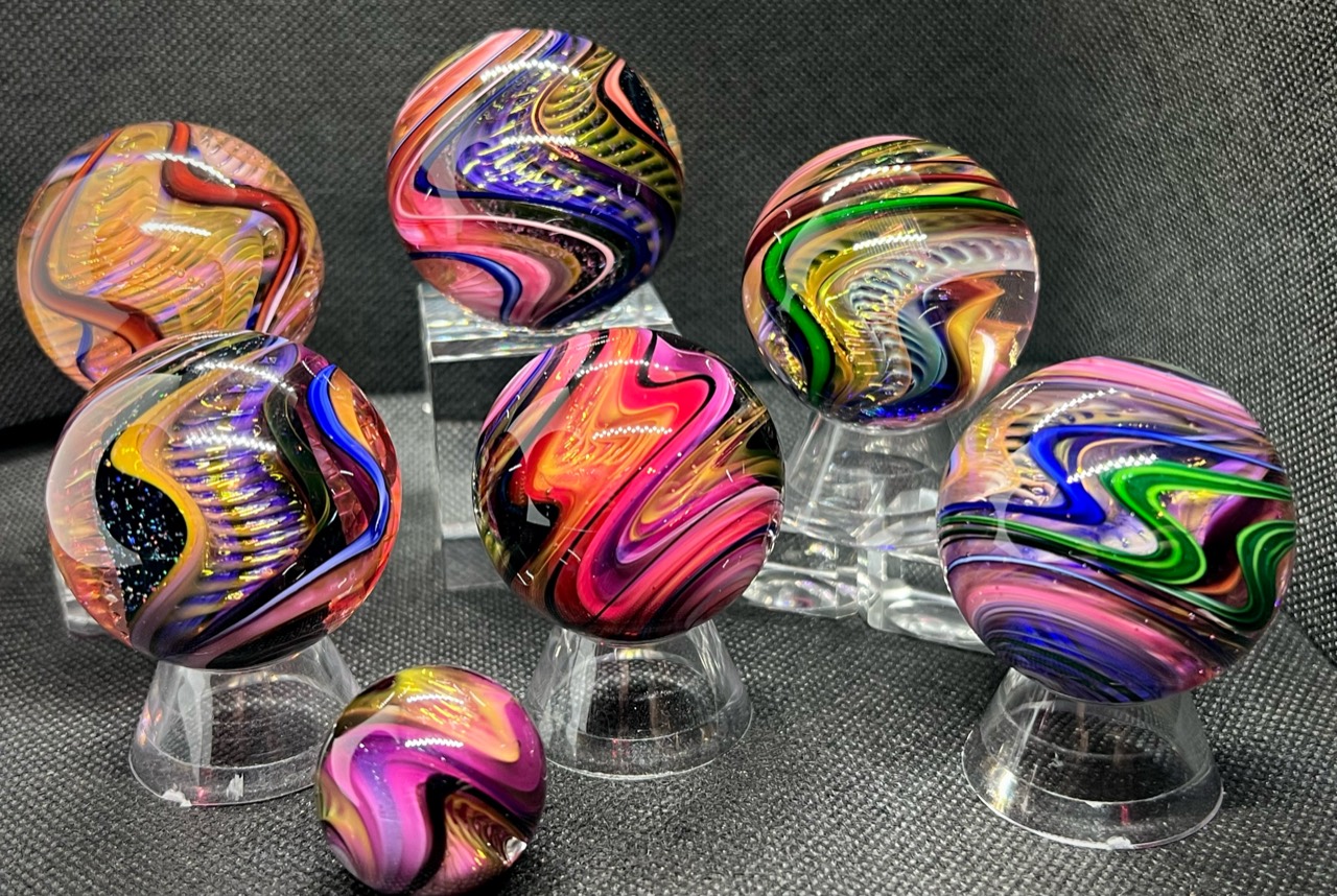 Aurora Borealis Space Wave: Close group portrait of seven Aurora Borealis Space Wave marbles, including the smaller front marble