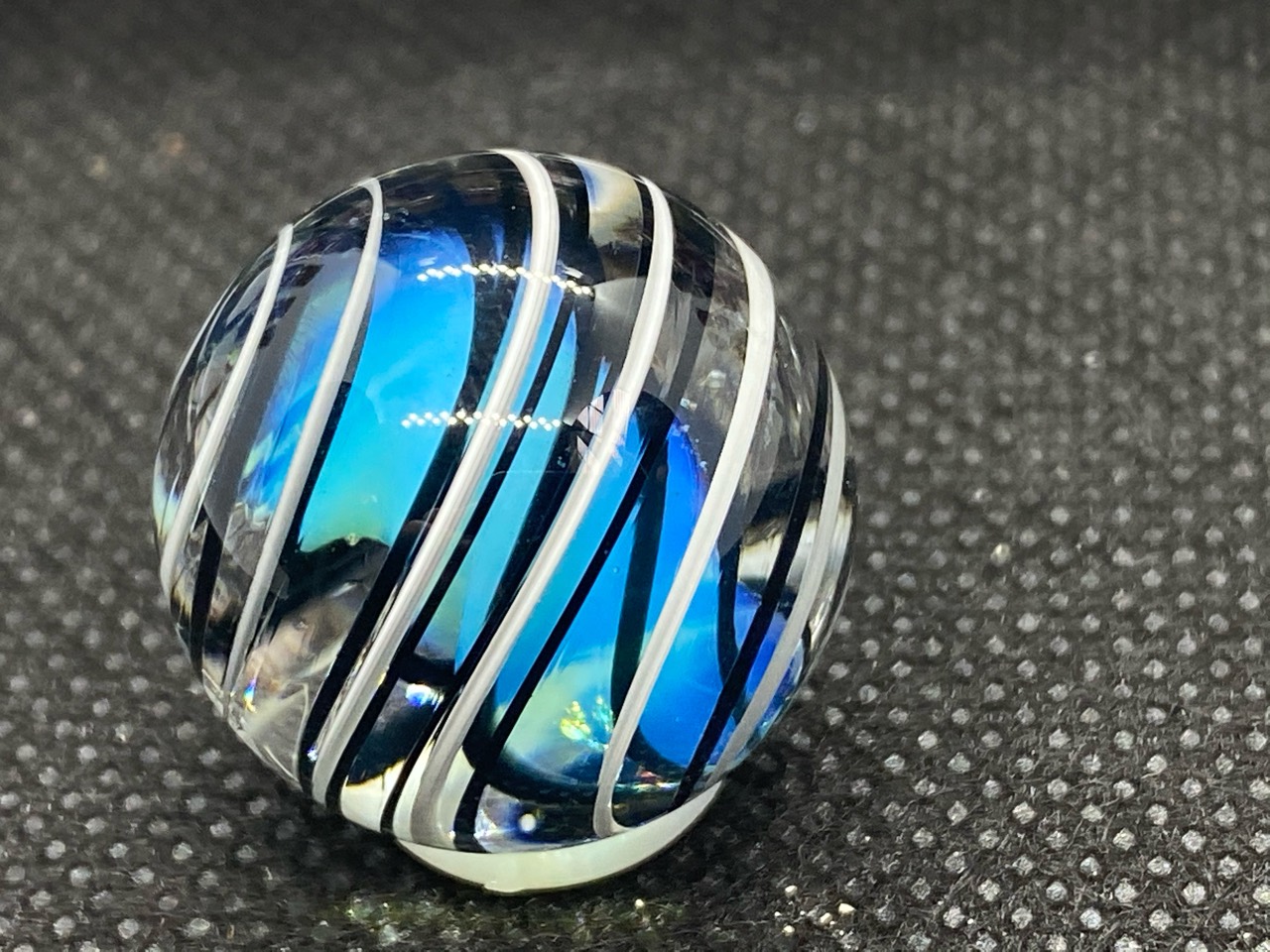 Blue Spiral Pocket Marble: Side view of white and dark spiral bands surrounding an aqua-blue center