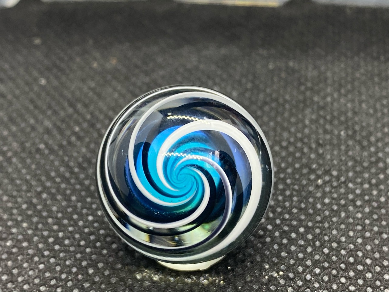 Blue Spiral Pocket Marble: End-on view of white and dark ribbons curling into a blue spiral