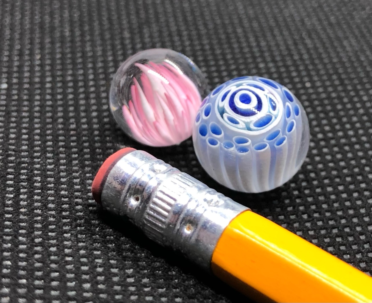 Blue & White Pattern and Pink Bloom Pee-wee Marbles: Alternate paired rotation showing elongated white forms around blue centers beside the pink bloom and pencil
