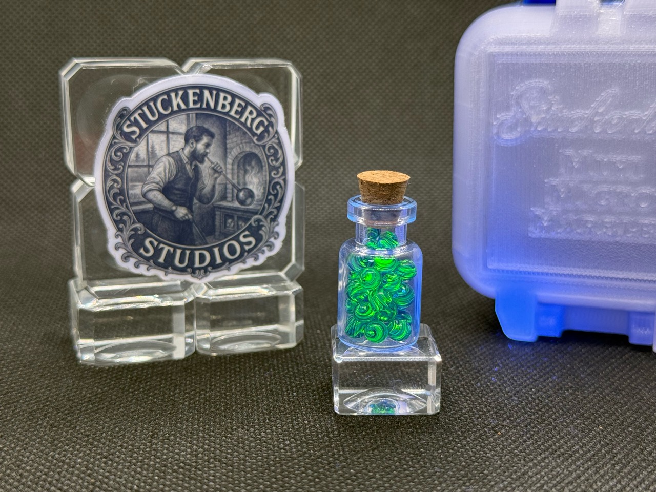 Cobalt UV Uranium Glass Mini Micro Marbles in their jar with green fluorescence revealed by a black light