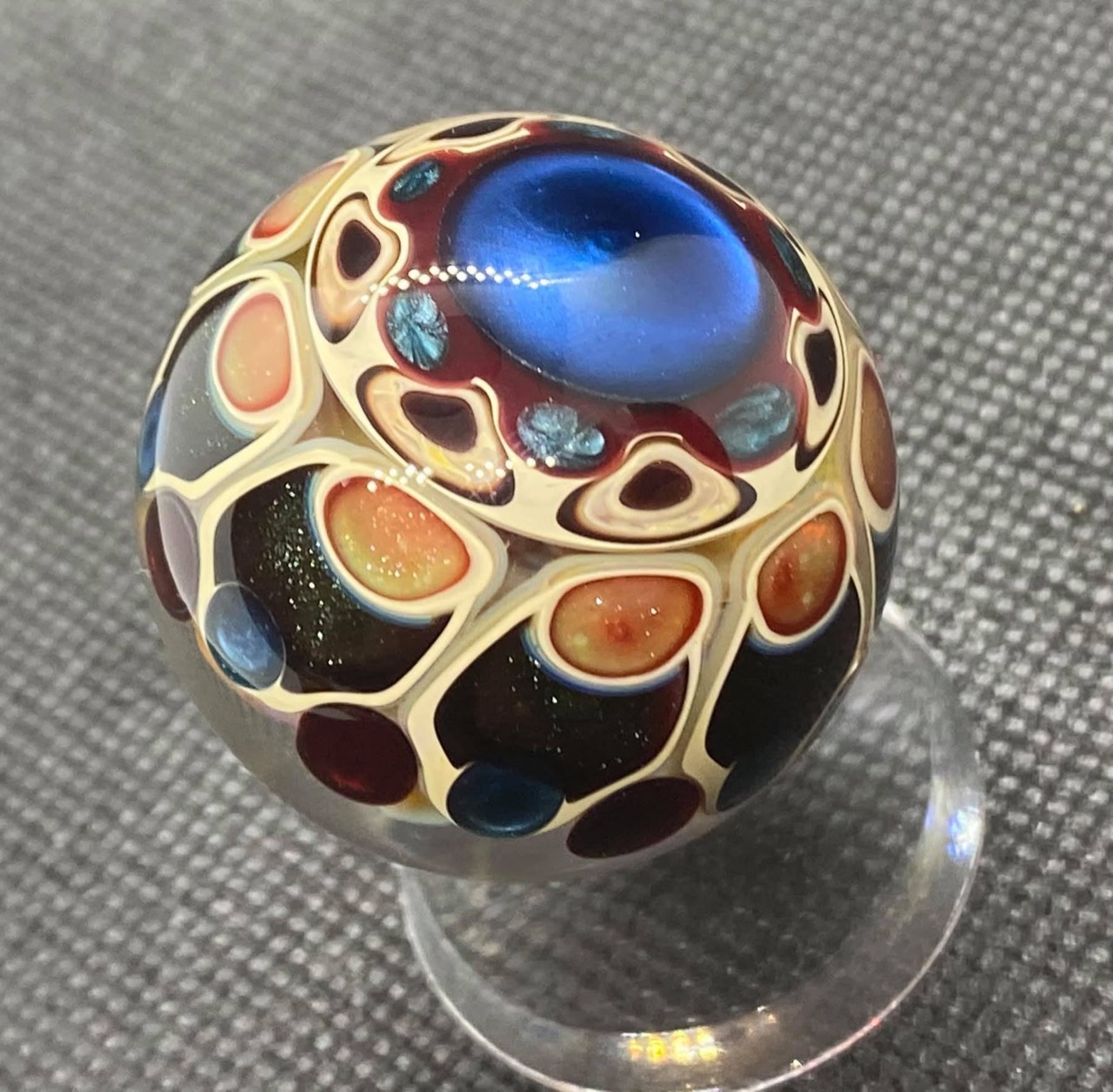 Dot Stack Marble — Over 100 Dots: full marble on a clear stand showing blue, amber, and ruby dot work