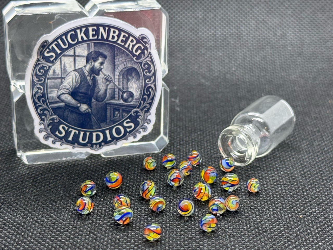 Wide view of Electric Rainbow Mini Micro Marbles with rainbow ribbons in ordinary light