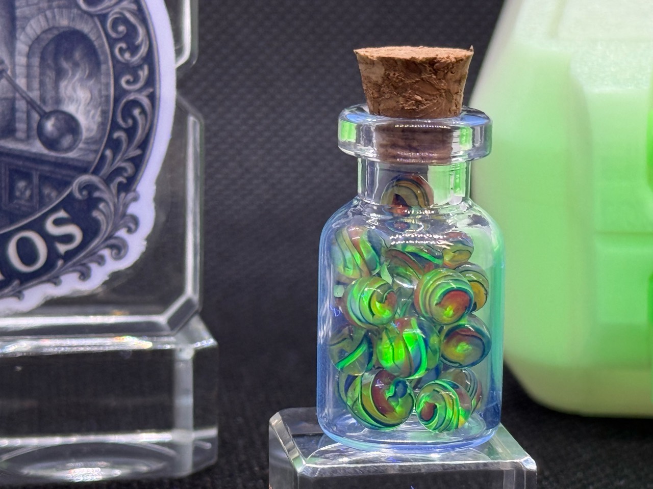 Close view of Electric Rainbow Mini Micro Marbles in their jar with green UV fluorescence