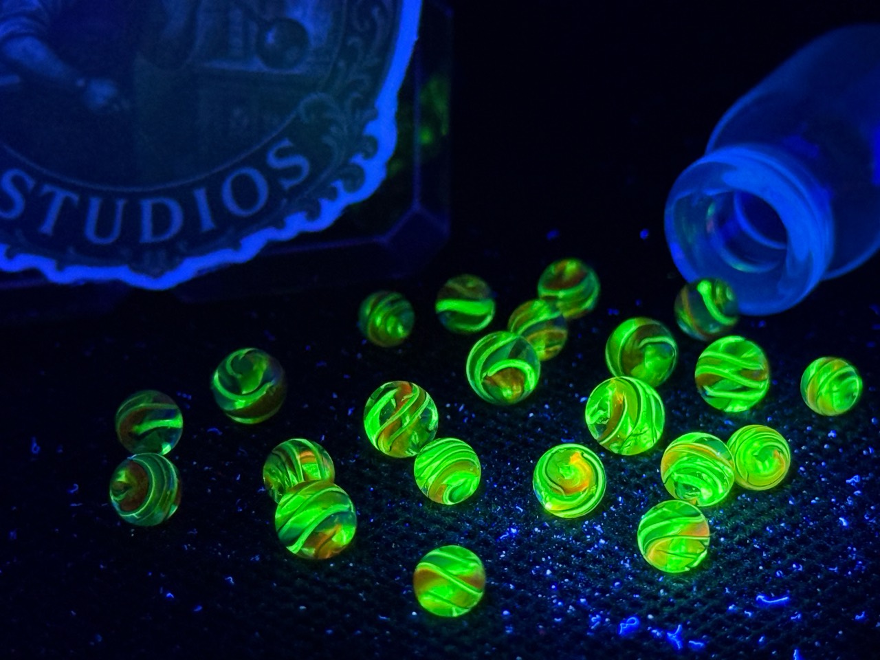 Loose Electric Rainbow Mini Micro Marbles glowing green under a black light