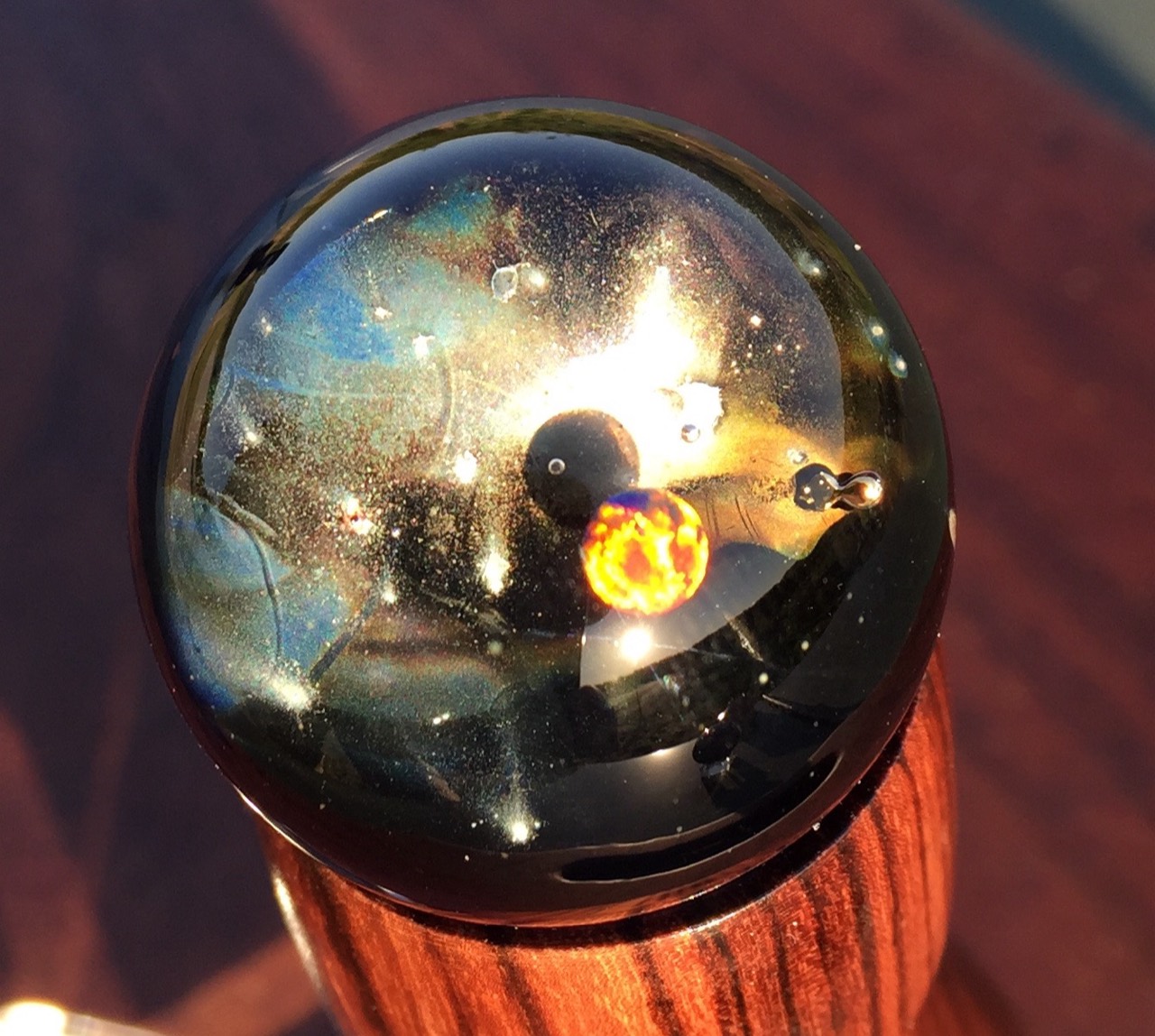 Fiery Opal Space Pocket Marble: Sunlit close view with a fiery yellow-orange opal, blue currents and fine cloud-like detail