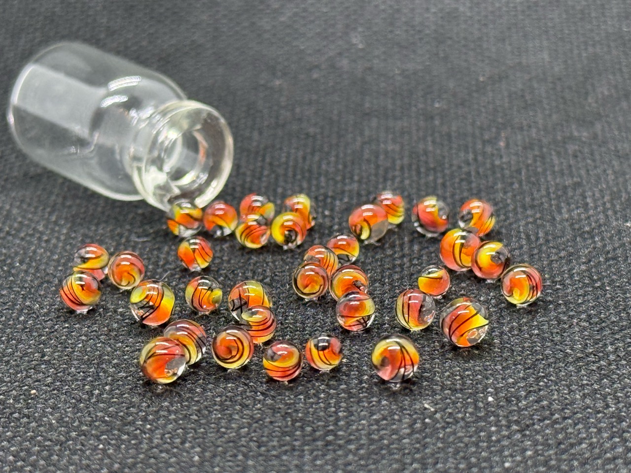 Fine Line Flame Mini Micro Marbles arranged beside their open glass jar