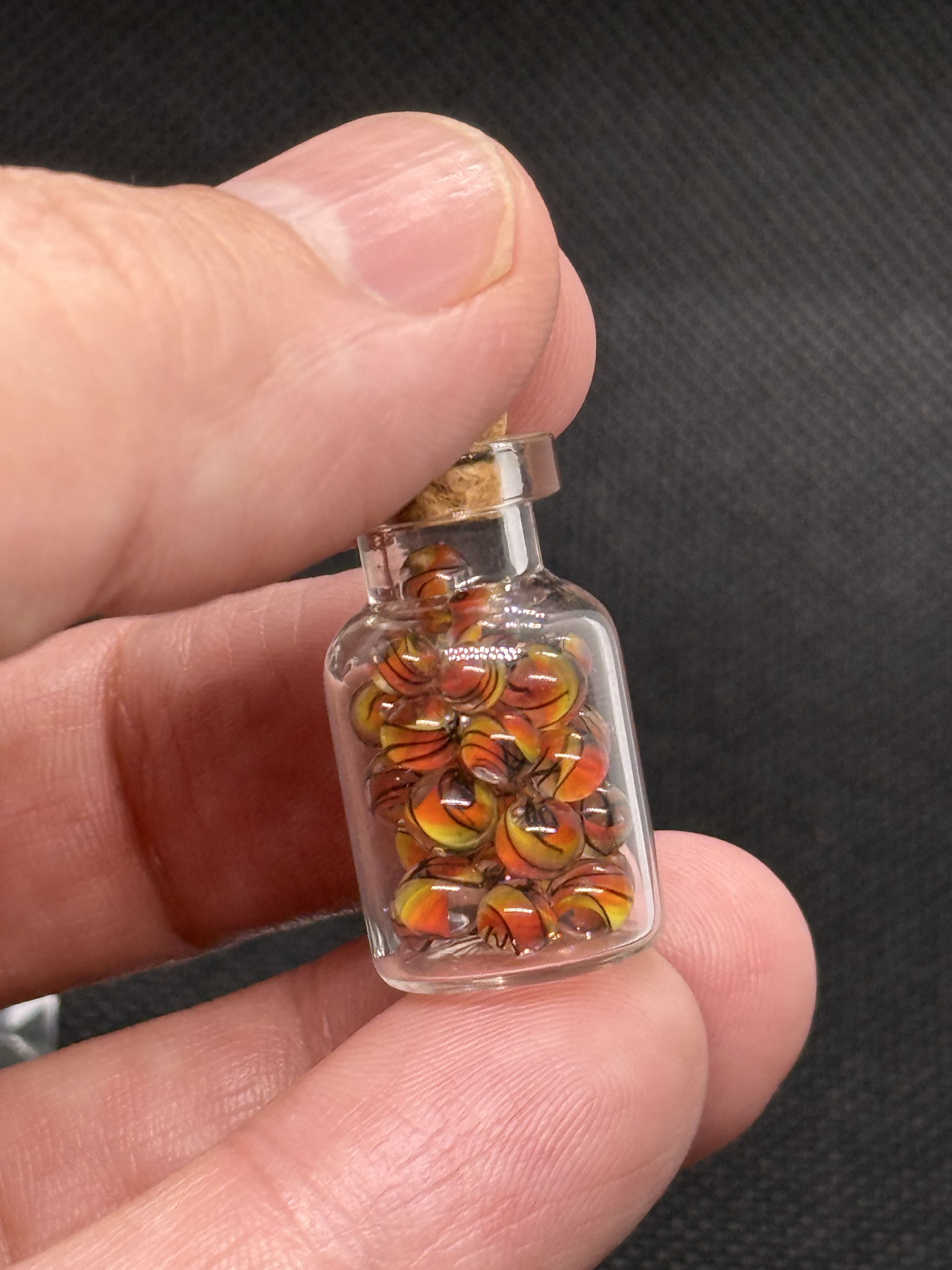 Fine Line Flame marble jar held between fingers for scale