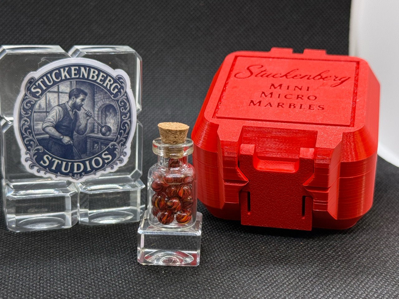Alternate full display of Fire Brick Ribbon Mini Micro Marbles beside their red hard case
