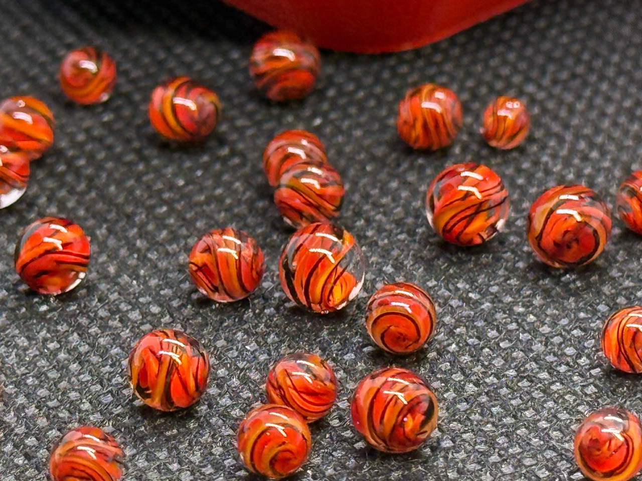 Close-up of layered red and orange ribbons with fine dark lines in Fire Brick Ribbon Mini Micro Marbles