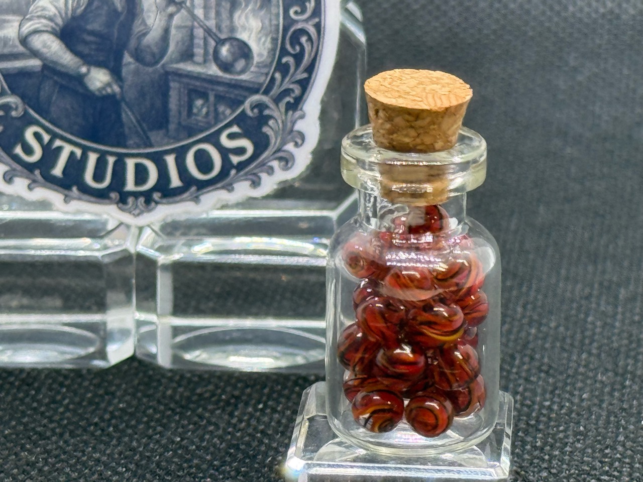 Close view of Fire Brick Ribbon Mini Micro Marbles inside their corked jar