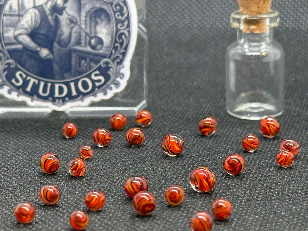 Alternate close view of loose Fire Brick Ribbon Mini Micro Marbles beside their jar and studio display