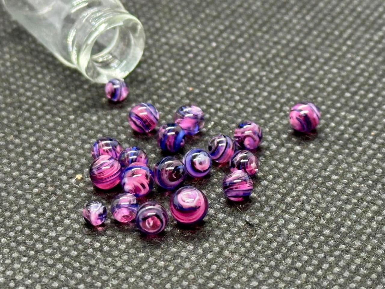 Galaxy Purple: pink, violet, and deep blue mini micro marbles gathered beside an open glass vial