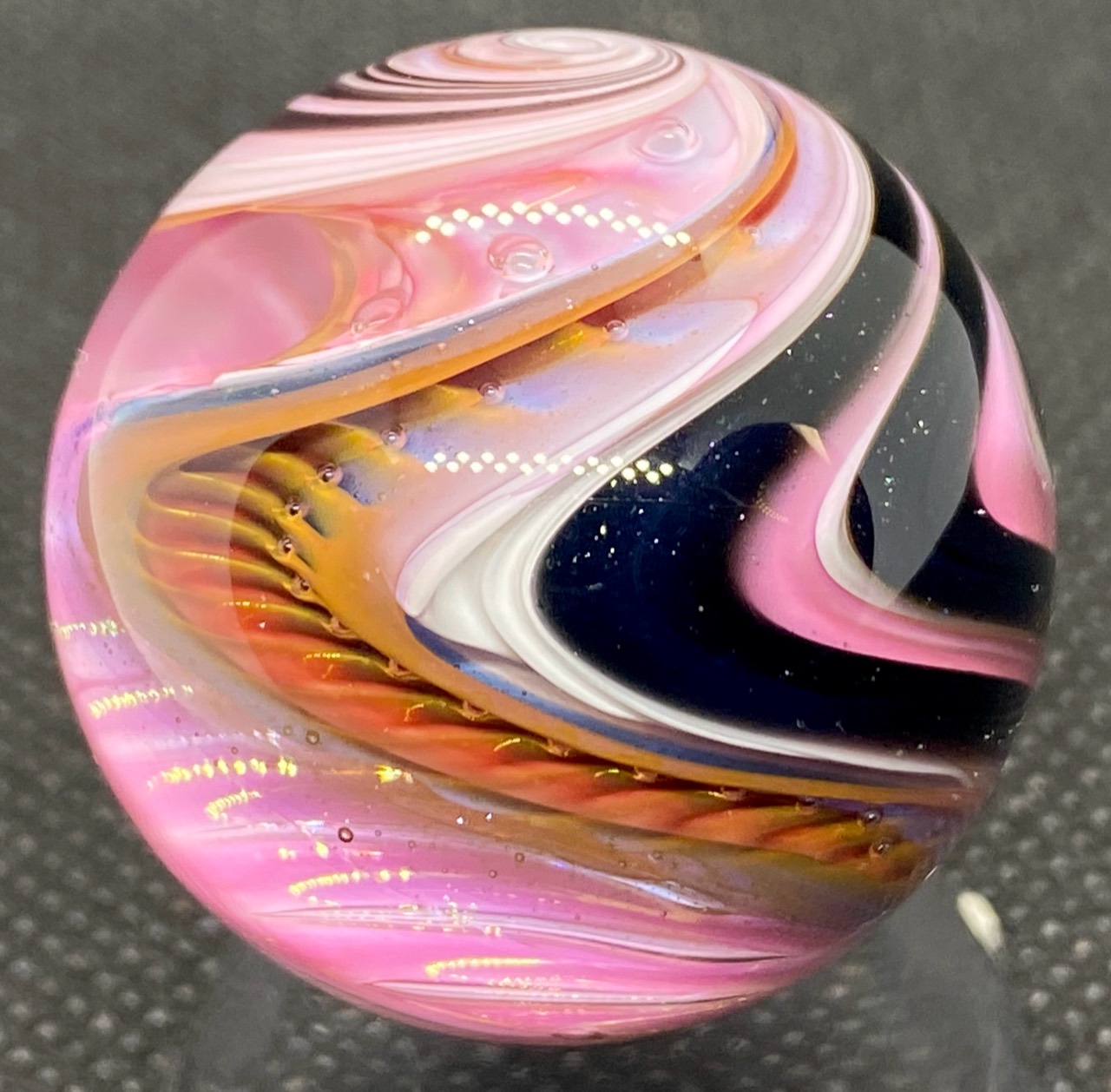 Gold Fume Switchback Marble: sweeping pink-toned and white bands above amber details and dark glass