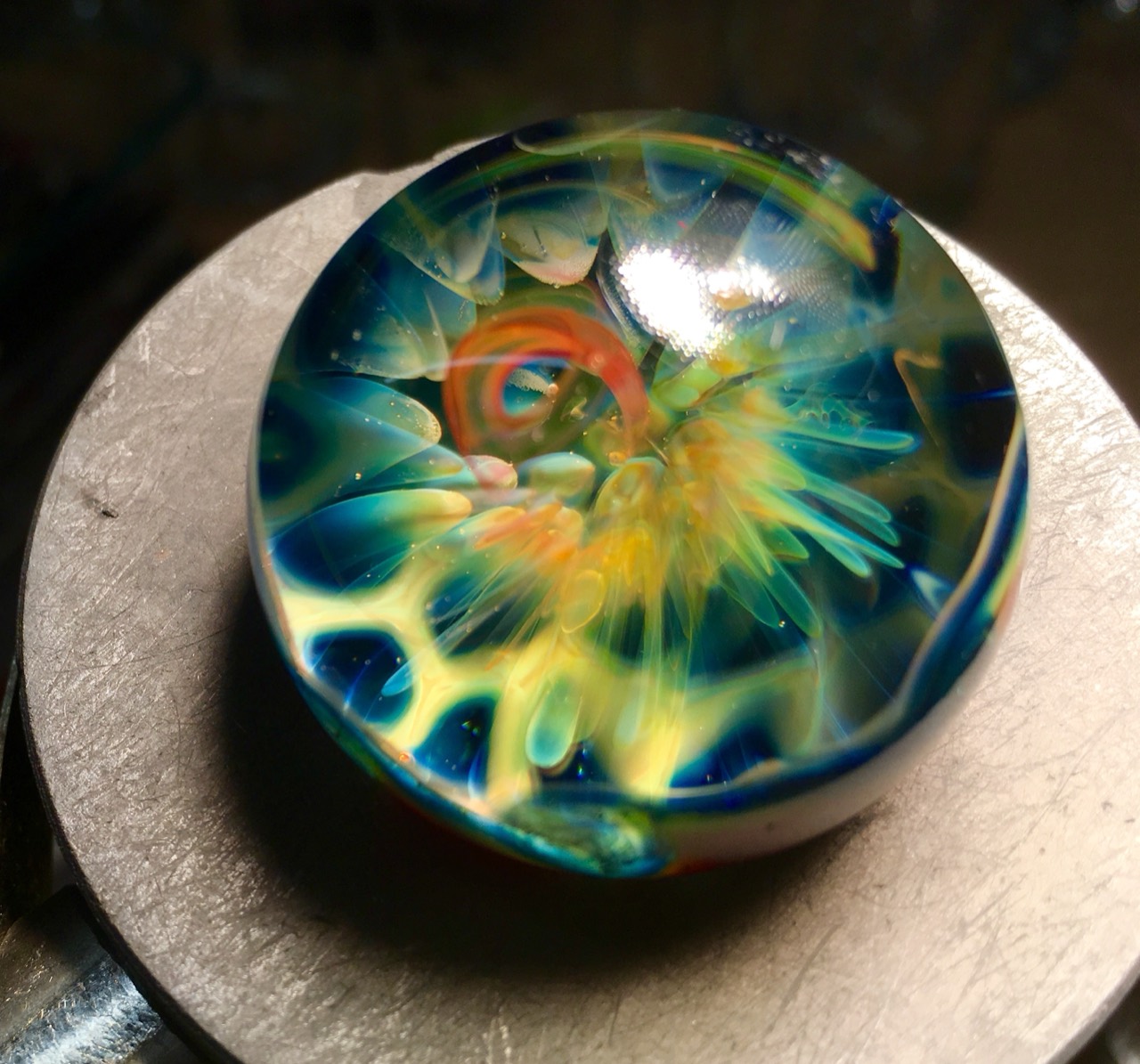 Gold & Silver Fume Marble with Red Elvis Slime Backing: Close front view of luminous blue-green petal-like forms and golden fume around a red-orange center
