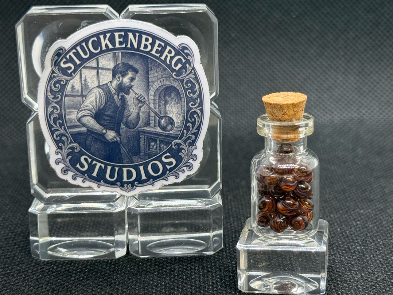 Close view of the corked Goldstone Mini Micro Marble jar beside studio branding