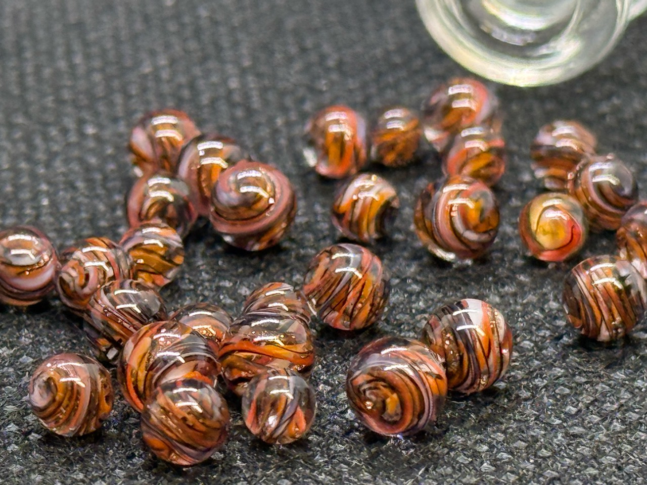 Macro view of copper, amber and dark ribbon patterns in Goldstone Mini Micro Marbles
