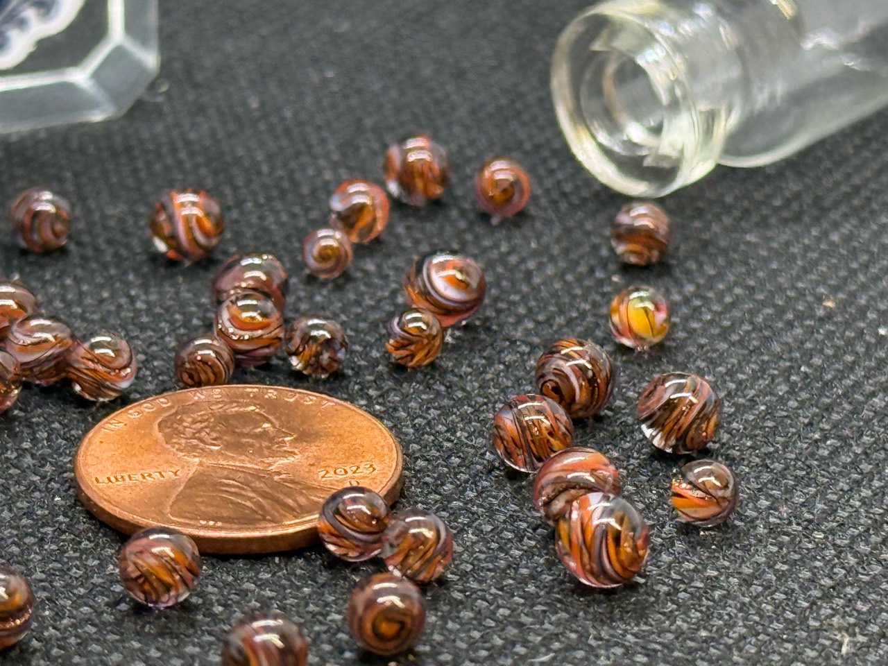 Close view of Goldstone Mini Micro Marbles beside a penny for scale