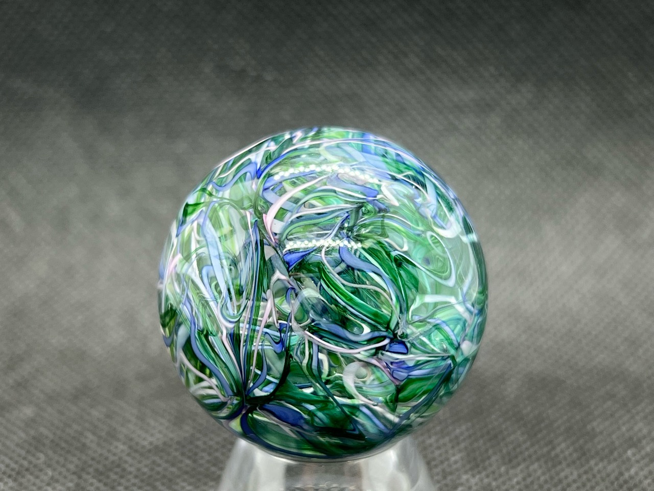 Green & Blue Ribbon Marble: Full view of blue, white and pale pink ribbons curling through transparent green glass