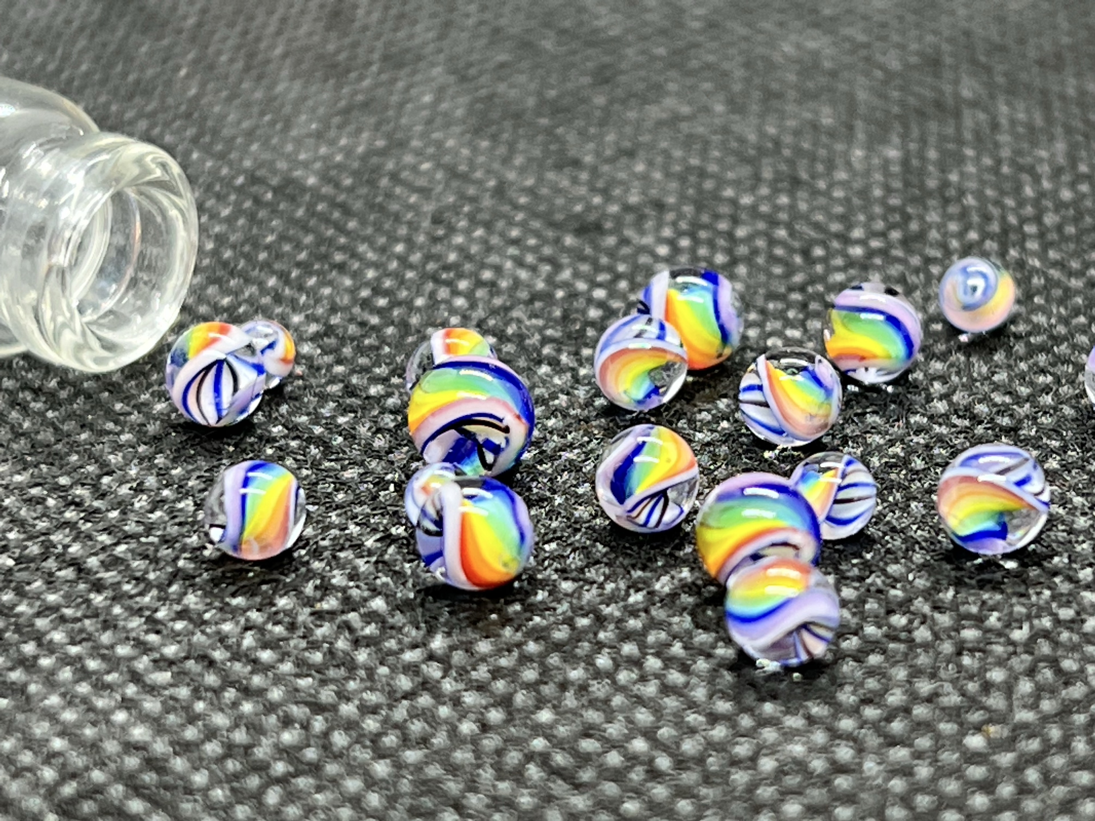 Legacy White Cloud Rainbow Mini Micro Marbles: Close low-angle view of White Cloud Rainbow micro marbles beside the open bottle