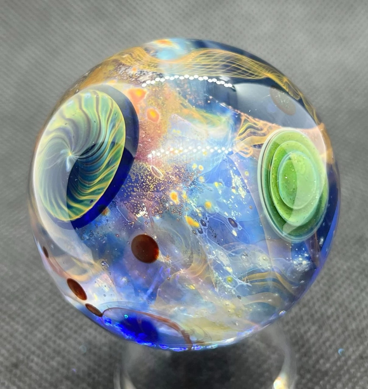 Living Planet Marble — 1.90 inches: watery blue depths with a green spiral planet and concentric green rings