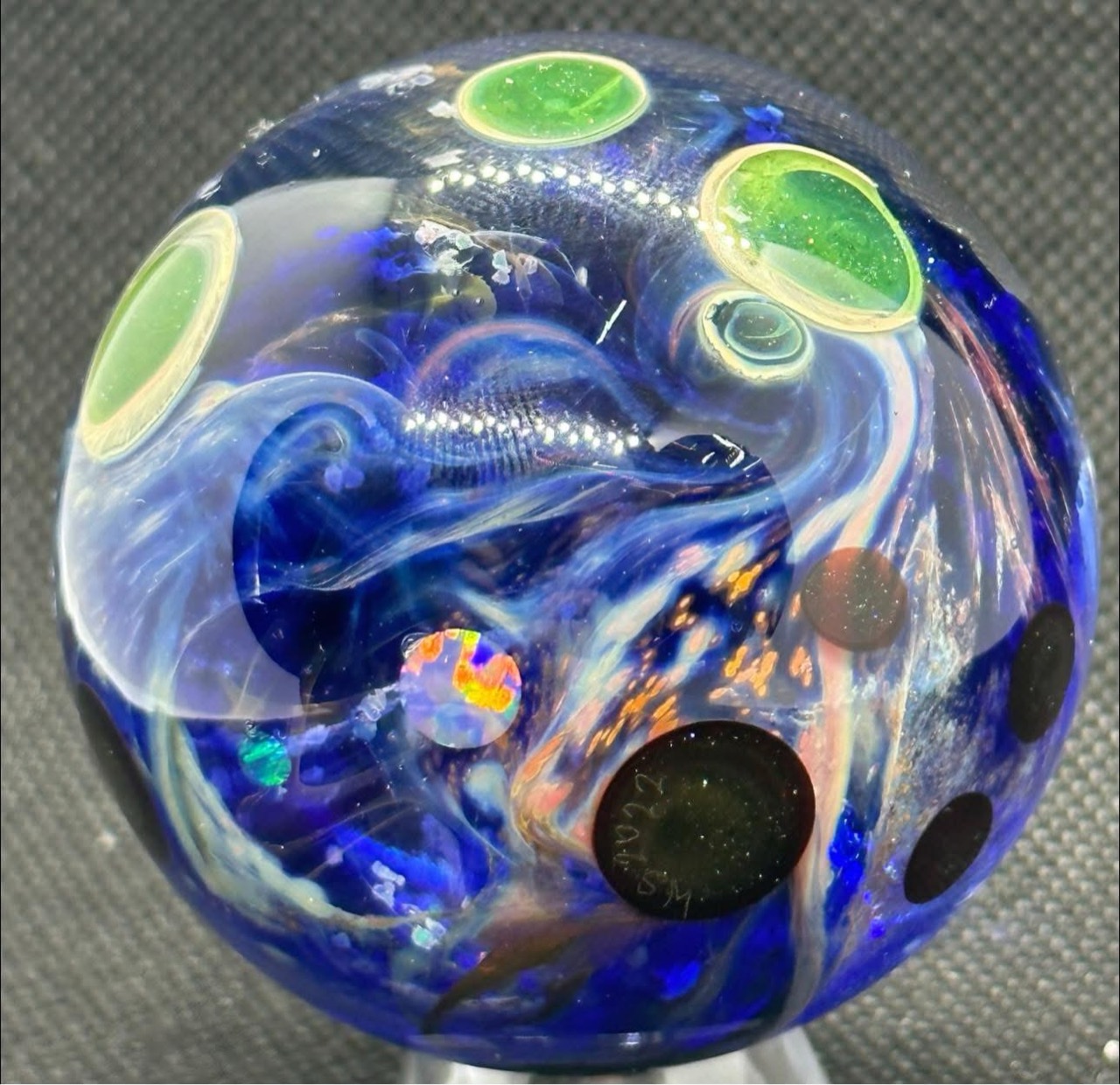 Living Planet Marble — 2.28 inches: deep blue glass with green planets, pale currents, and opal inclusions