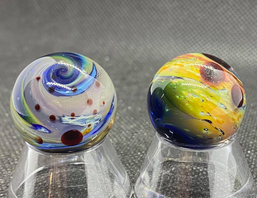Living Planet Pocket Marbles (July 22, 2021): living planet pair with a pale blue spiral and golden-green terrain
