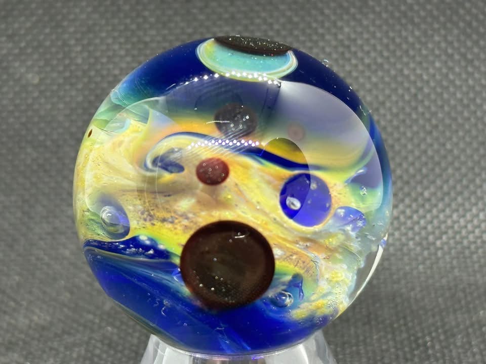 Living Planet Space Marble #5 (2023): golden swirls and dark planet forms above deep blue glass