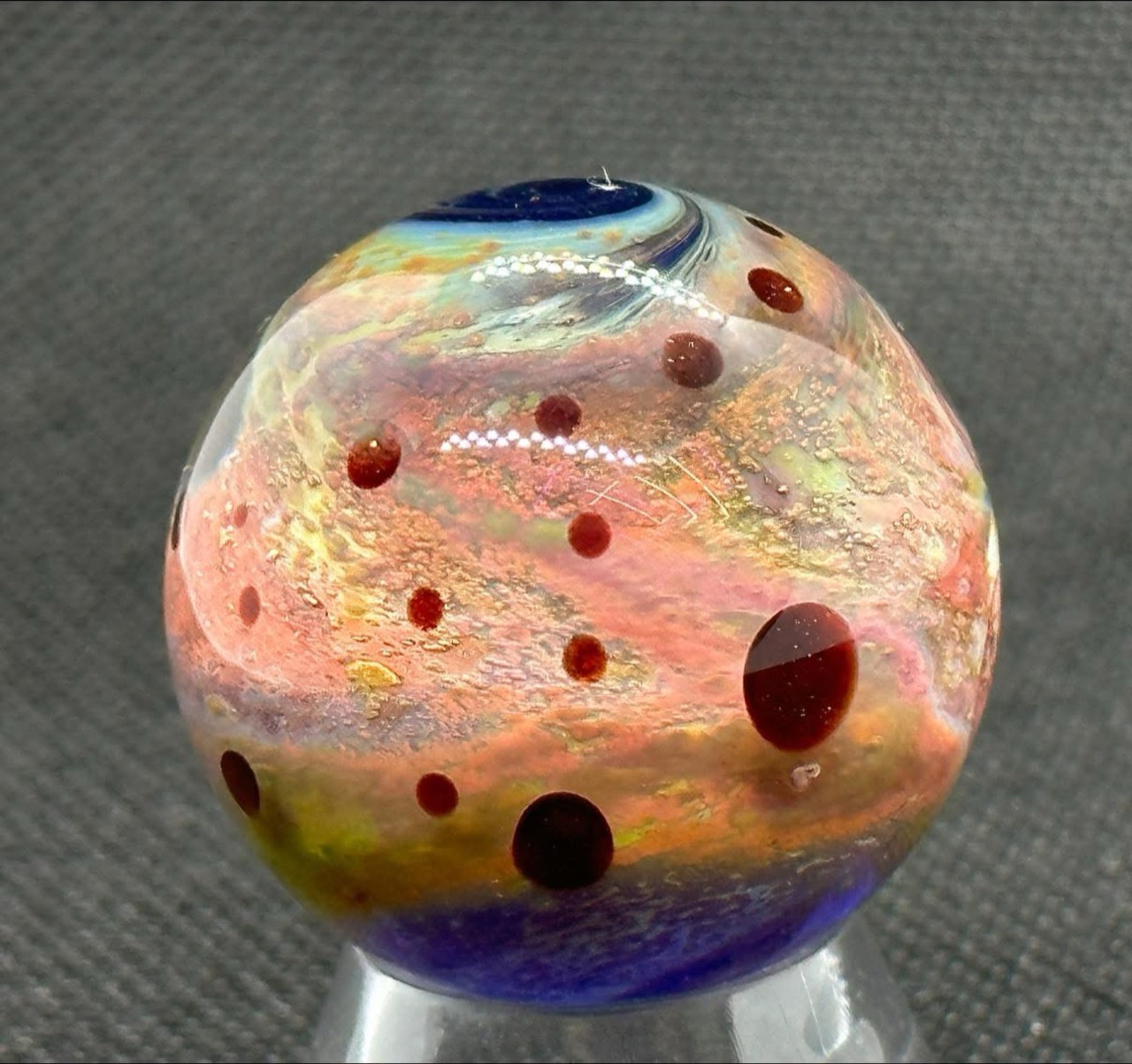 Living Planet Space Marble (Early 2023): rose and golden layers filled with small dark red planets