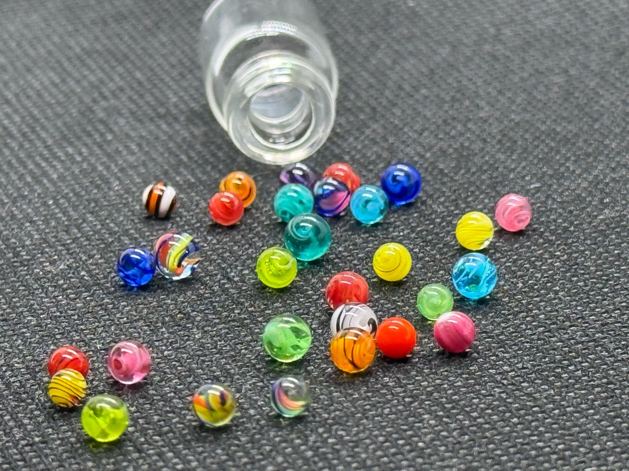 Close view of Mixed Colors Mini Micro Marbles arranged beside the mouth of their open jar