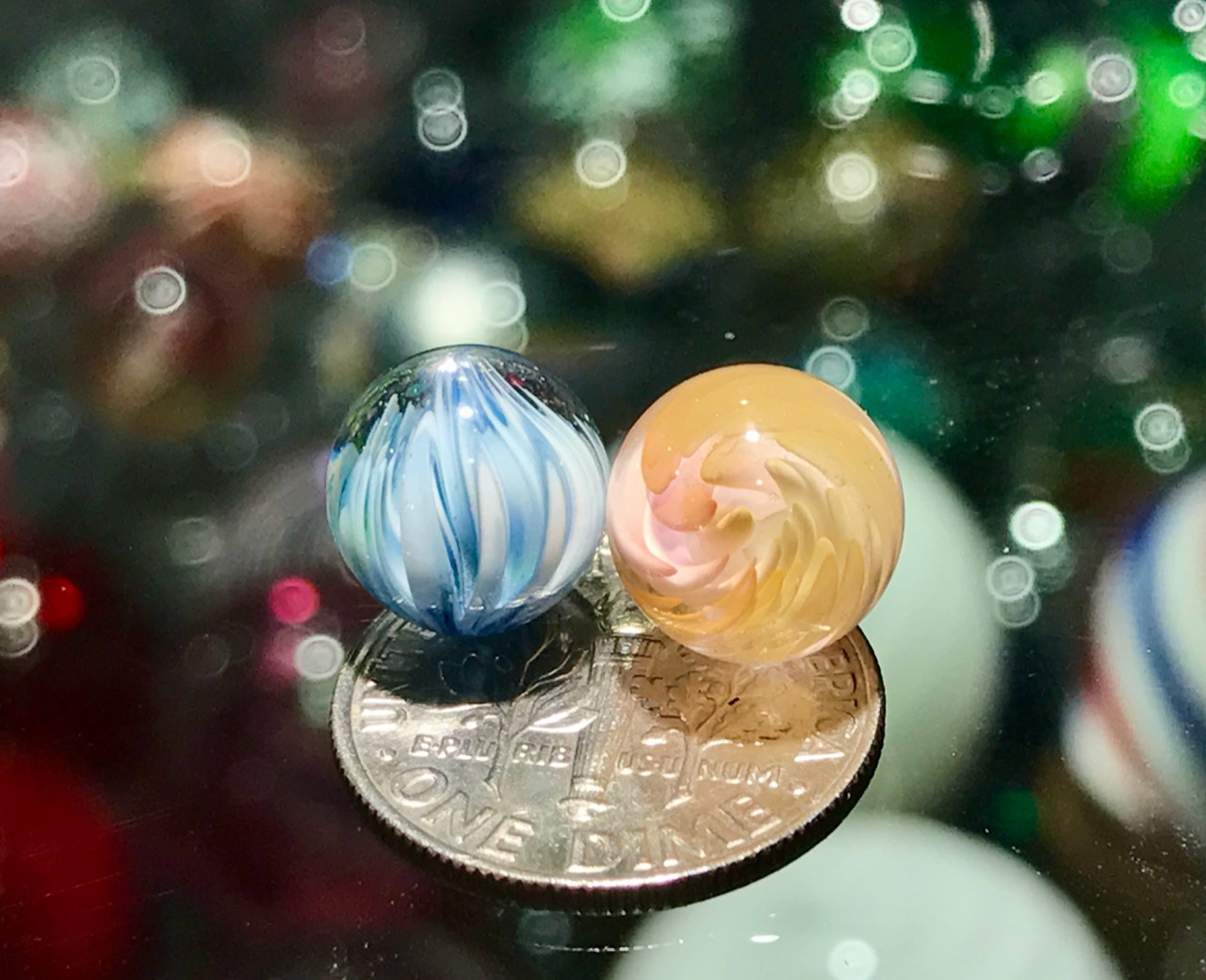 Onion Skin & Gold–Silver Fume Bloom Pee-wee Marbles: Front view of the blue-and-white onion skin beside the warm gold-and-silver fume bloom on a dime