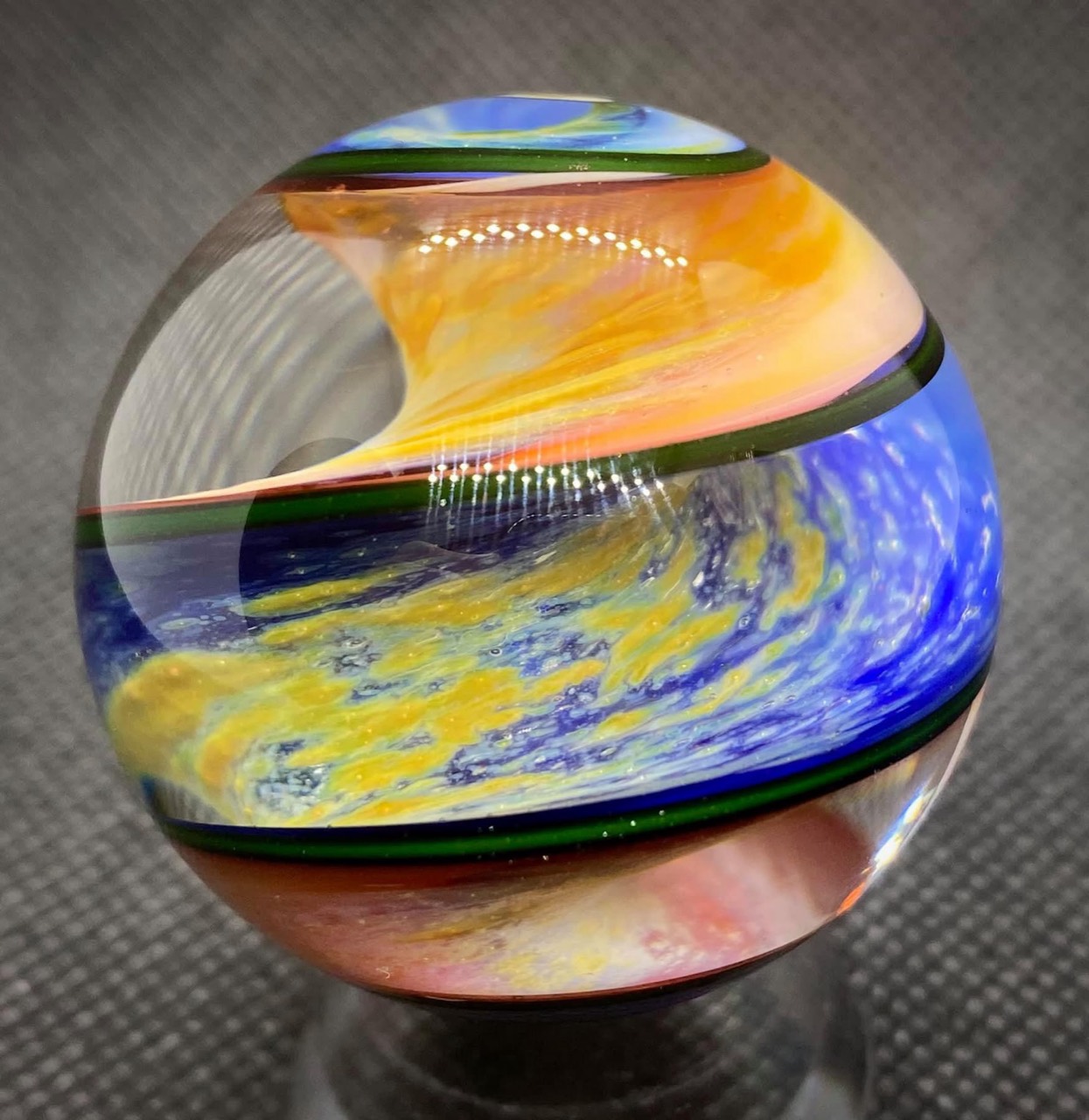 Parallel Dimension of Space Marble: golden clouds sweep through blue and peach-pink space ribbons edged in green