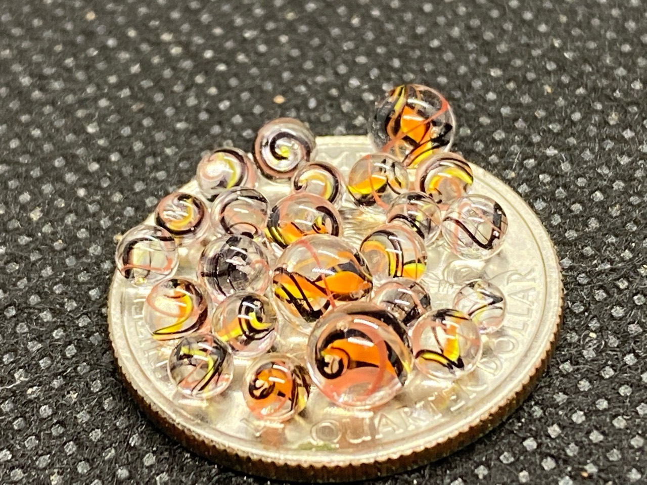 Peach & Amber Ribbon Mini Micro Marbles: Close view of peach and amber micro marbles gathered on a quarter for scale