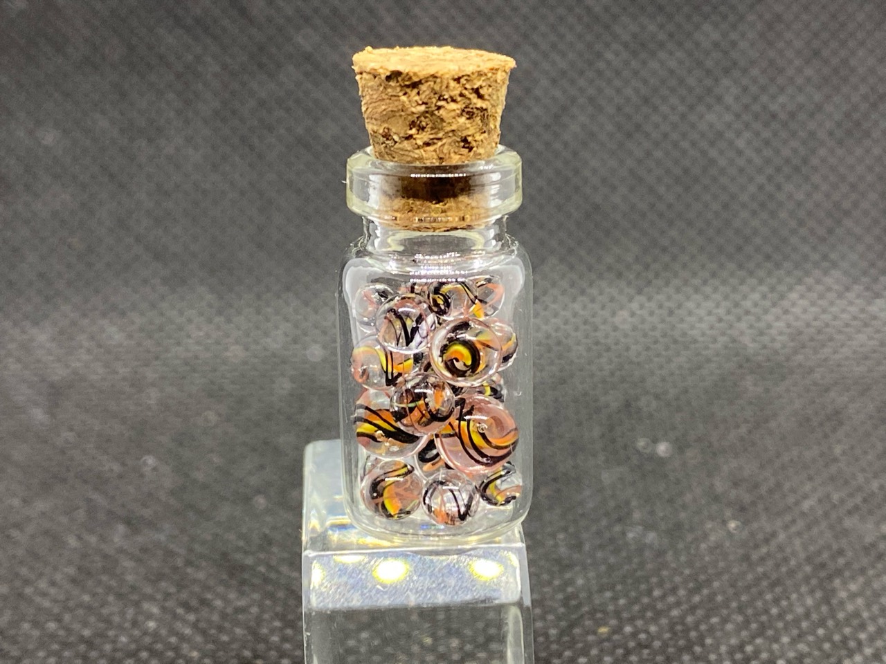 Peach & Amber Ribbon Mini Micro Marbles: Studio bottle view showing fine peach, orange, yellow and black ribbons in clear micro marbles
