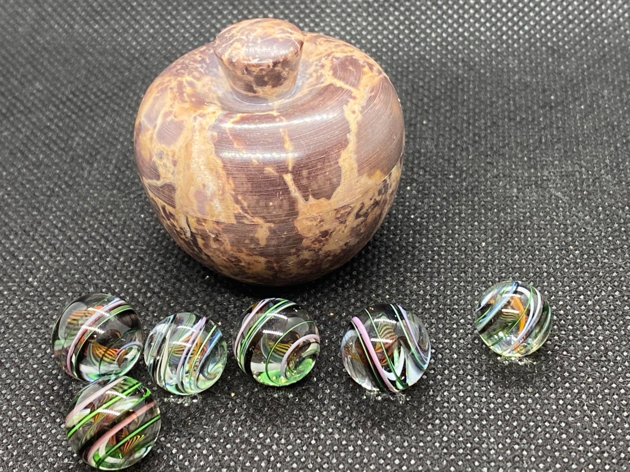 Pee-wee Marbles — April 2020: six ribbon-patterned pee-wee marbles beside a closed brown and tan container