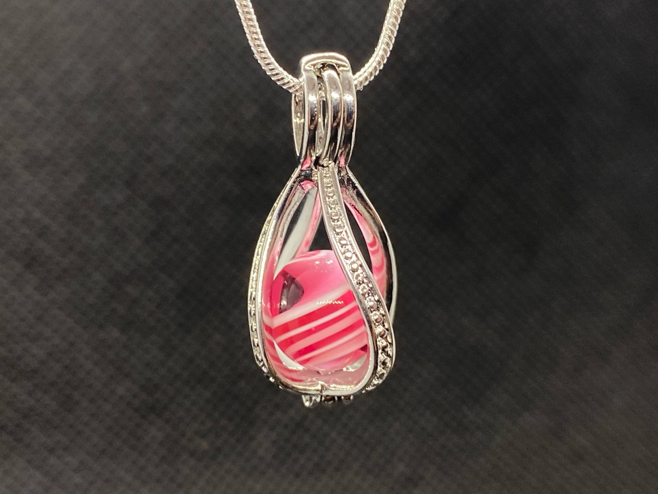 Pink Ribbon Pee-wee Marble in a Pearl Cage: Close pendant view showing the ruby ribbon and fine white stripes inside the pearl cage