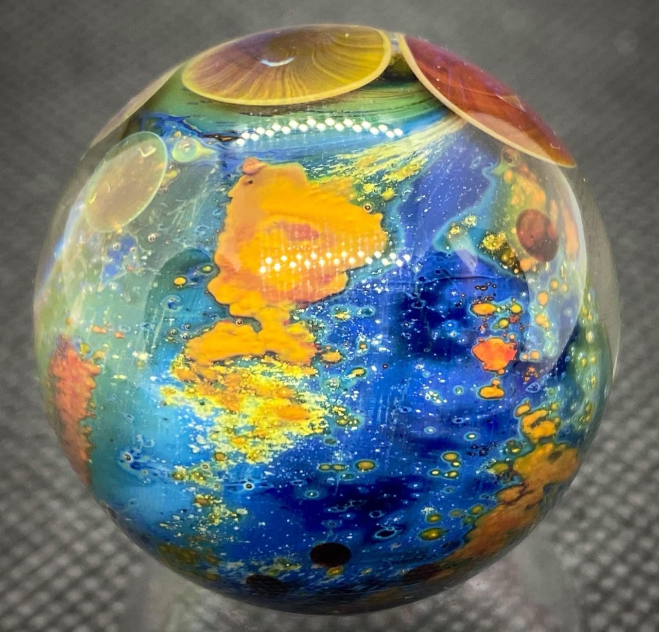 Planetary Space Pocket Marble: blue glass with orange formations beneath amber and rose planets