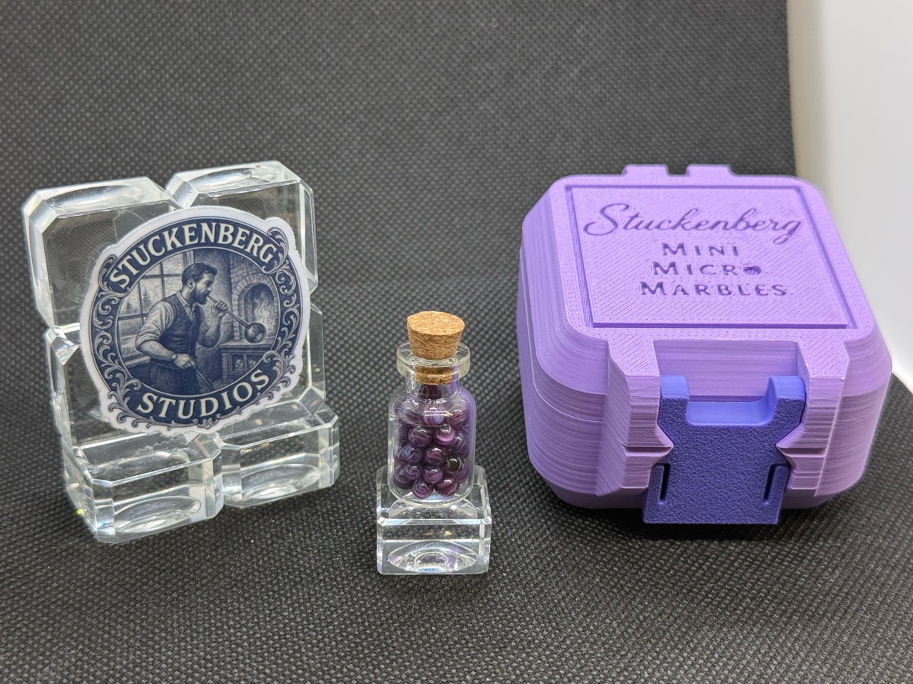Purple Dream Mini Micro Marbles in a corked jar beside the studio display and purple hard case