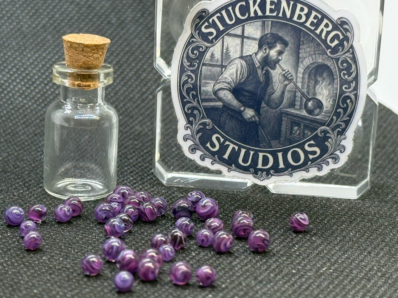 Purple Dream Mini Micro Marbles beside an empty corked jar and studio display