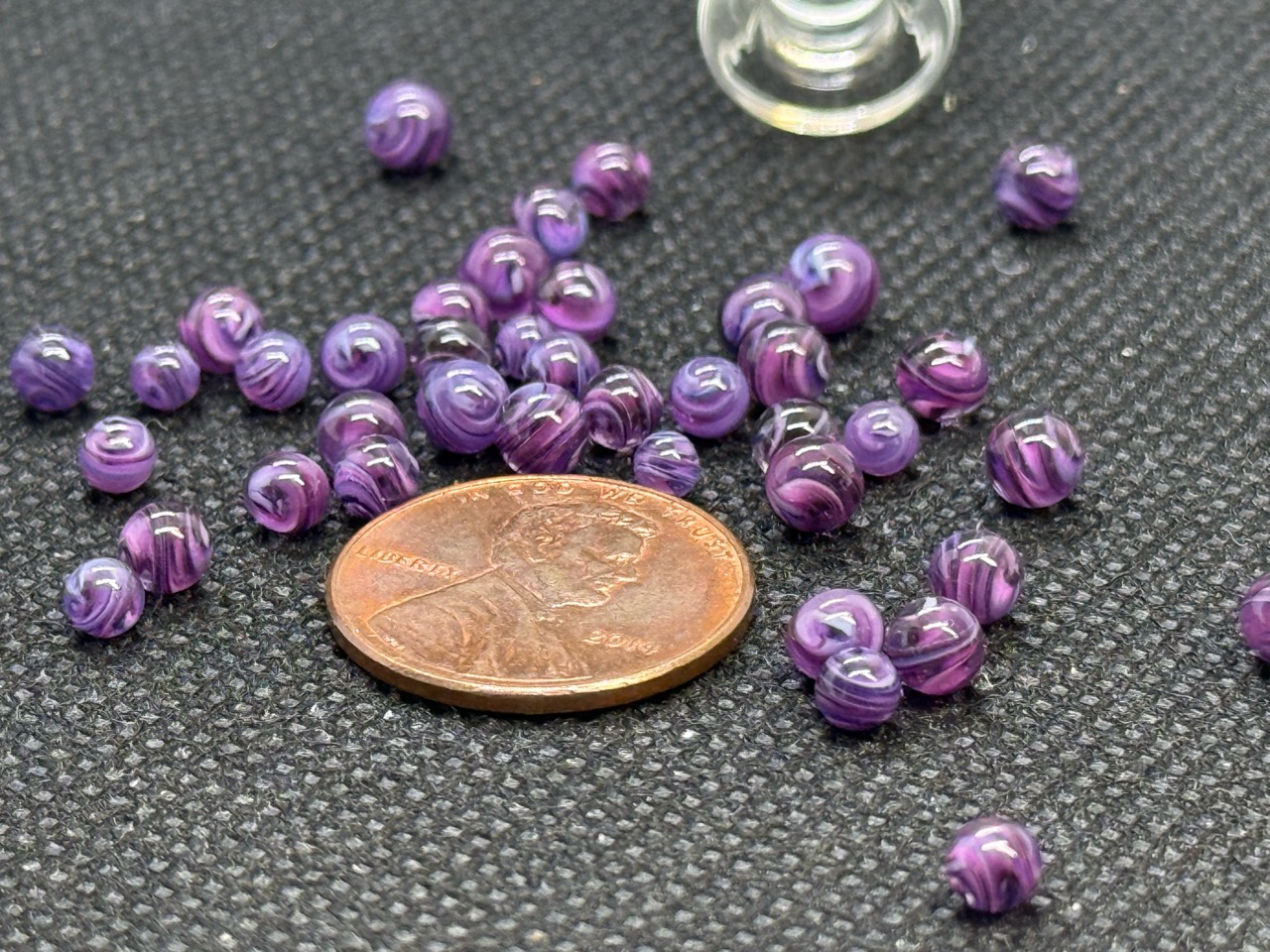 Alternate close view of Purple Dream Mini Micro Marbles beside a penny for scale