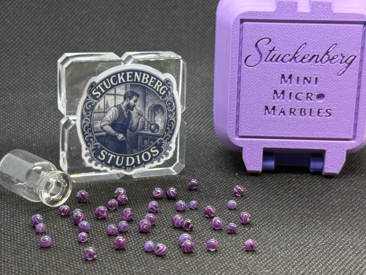 Loose Purple Dream Mini Micro Marbles beside the studio display and purple hard case