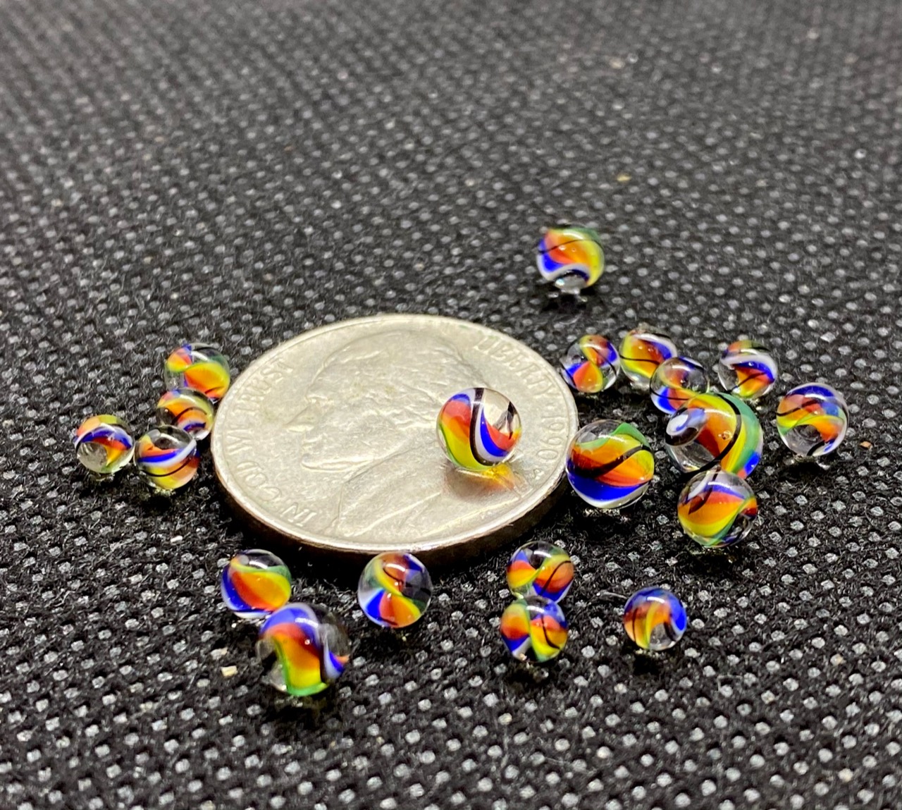 Rainbow Micro Marbles: Close group of rainbow micro marbles on and around a quarter for scale